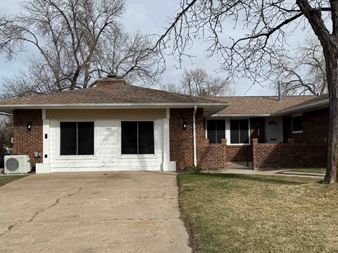 A house with a white garage door and a brick wall.