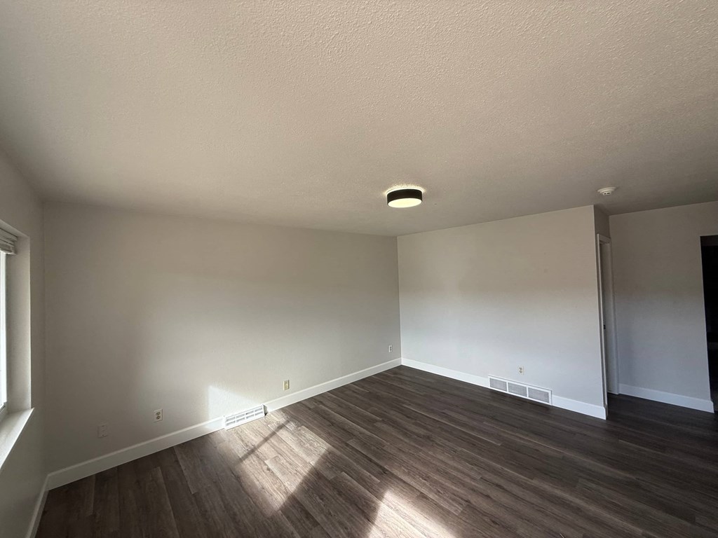 A room with wooden flooring and white walls.