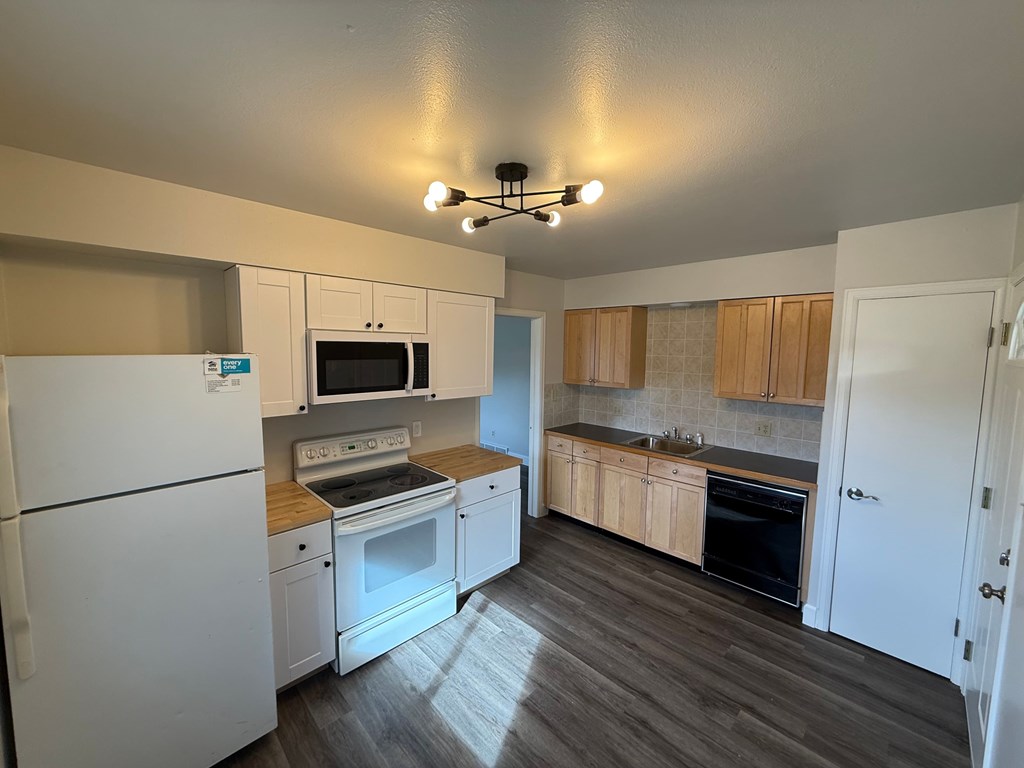 A kitchen with white appliances and wooden cabinets.