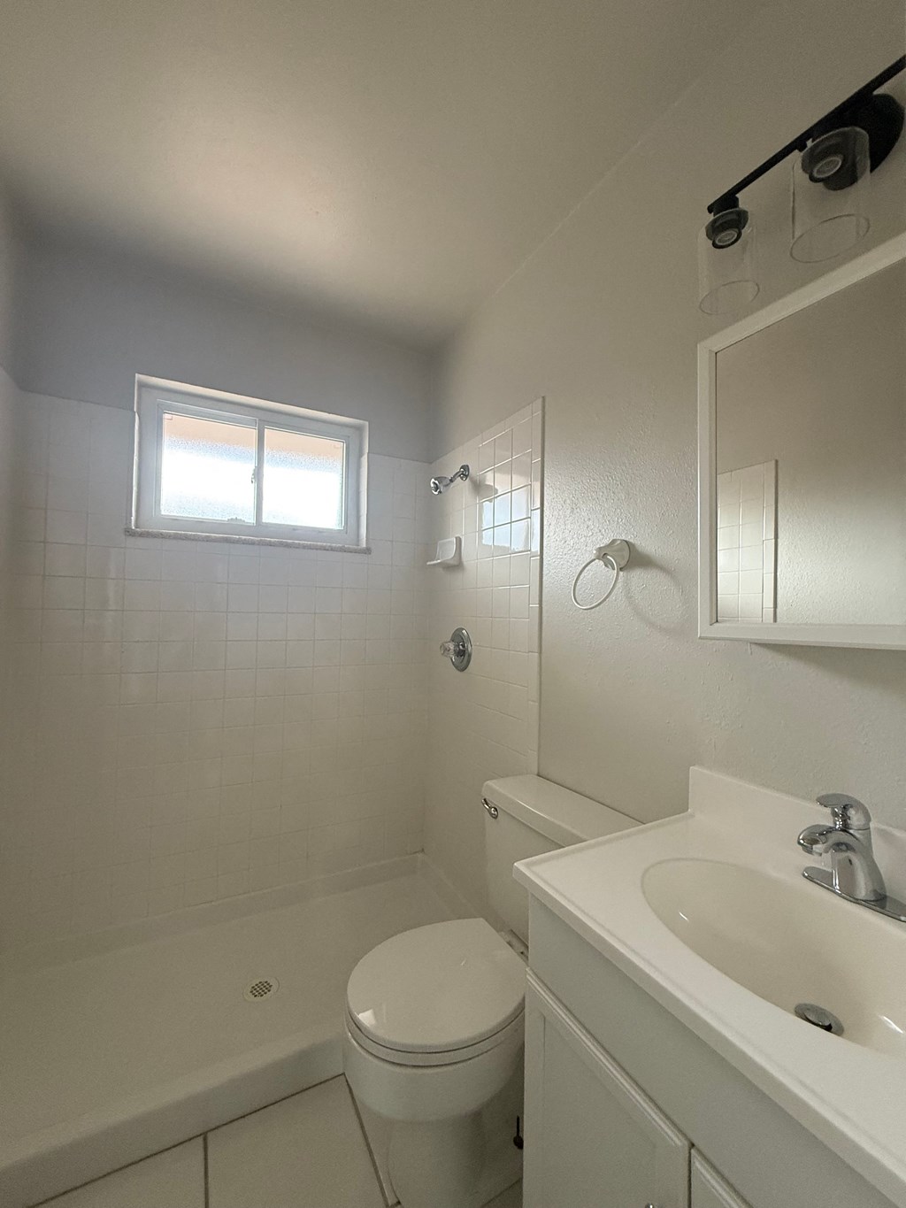 A white bathroom with a toilet, sink, and mirror.