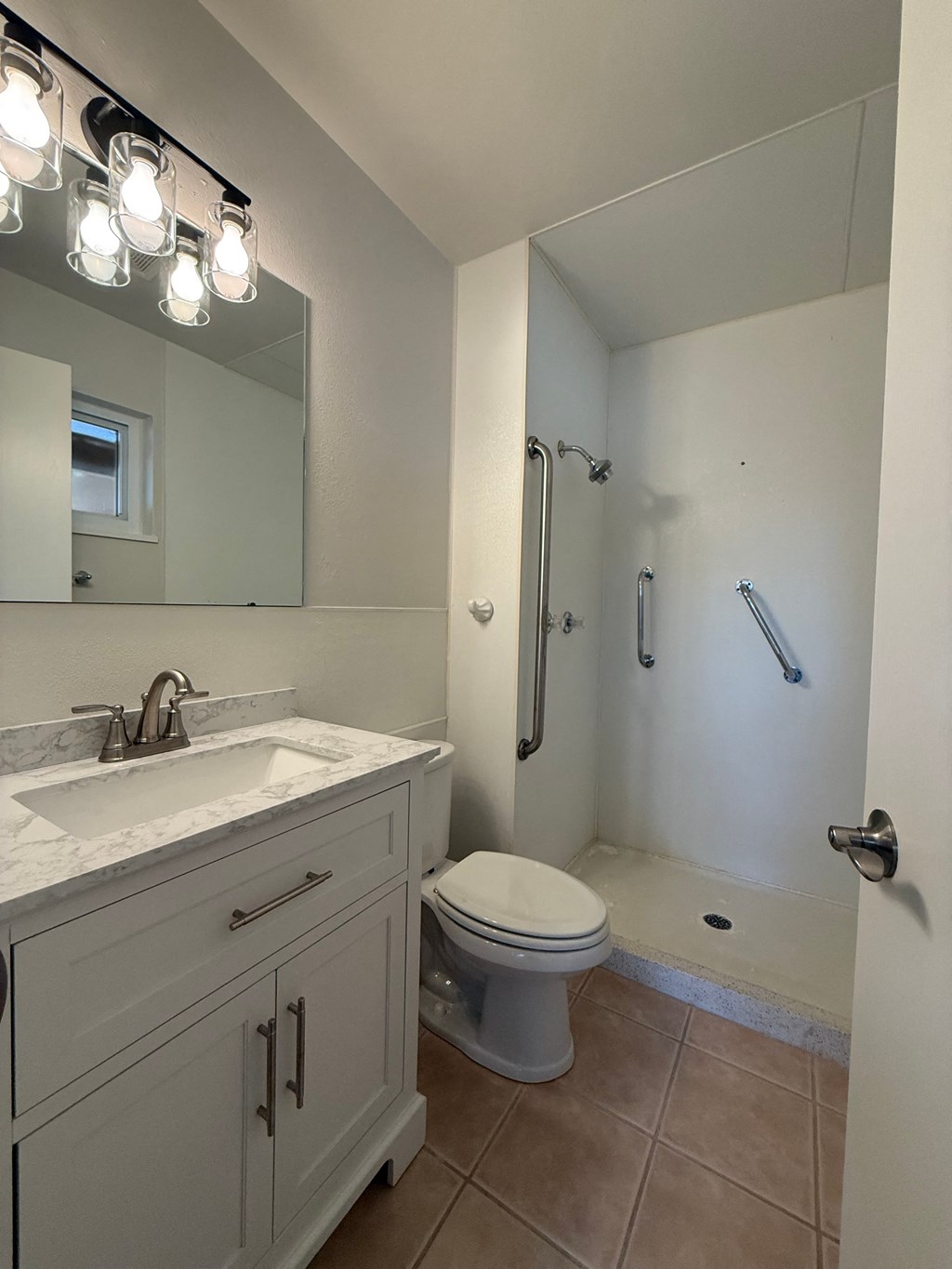 A white bathroom with a sink, toilet, and shower.