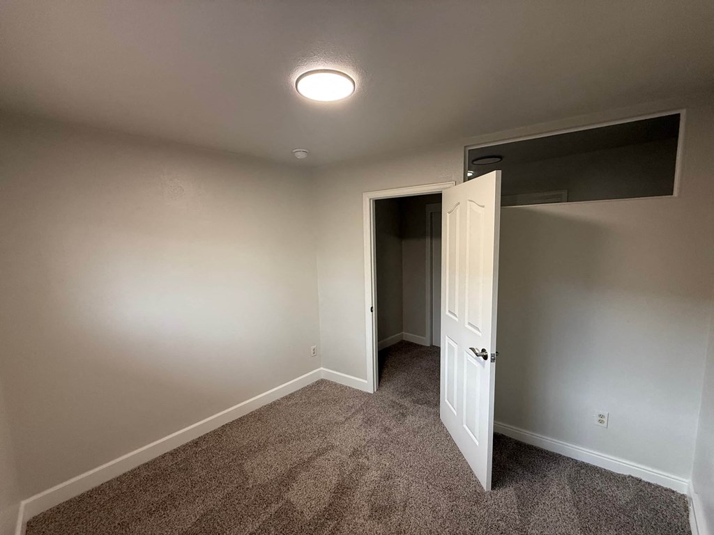 A room with a carpeted floor and a white door.