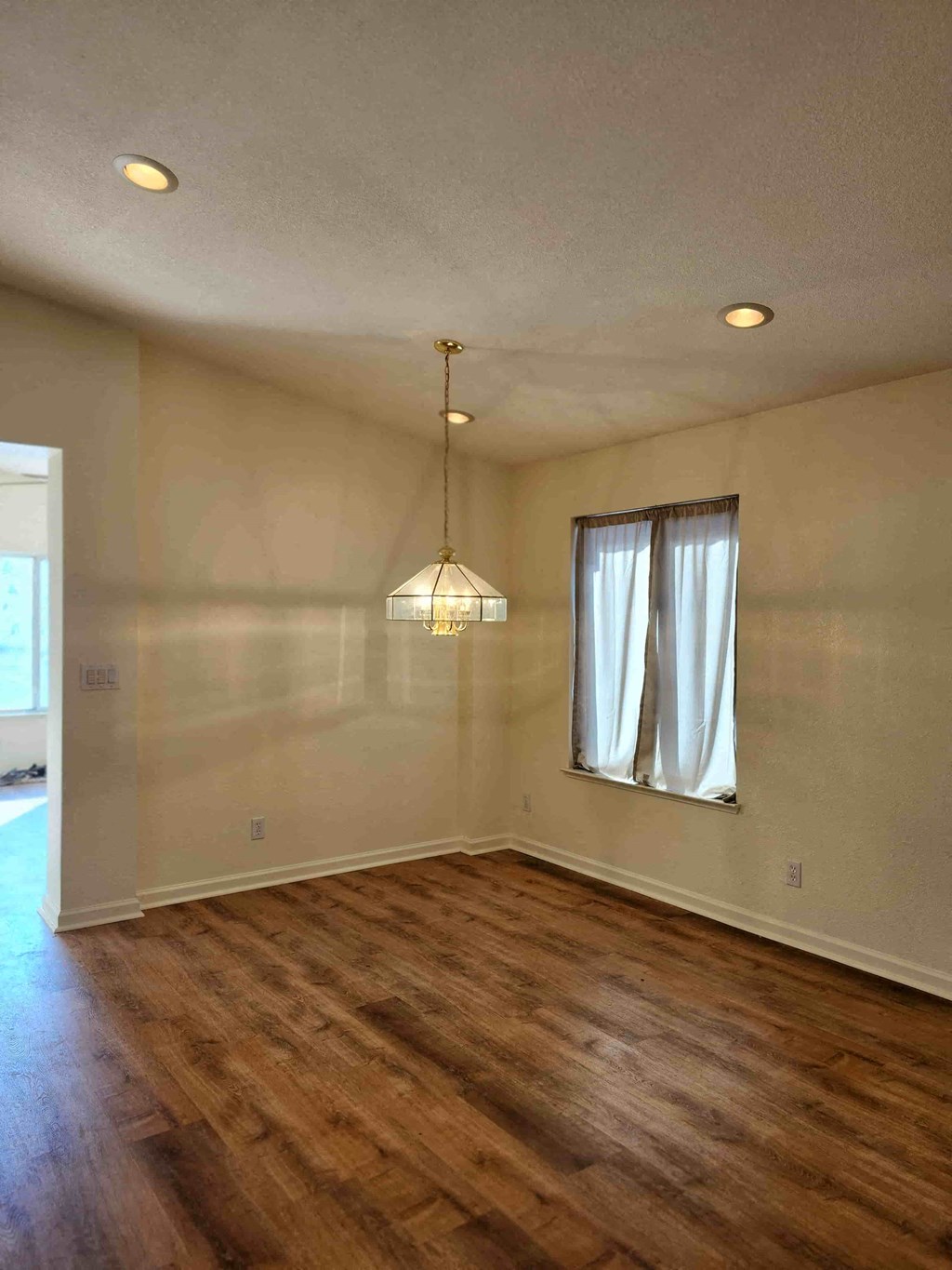 A room with wooden floors and a hanging light fixture.