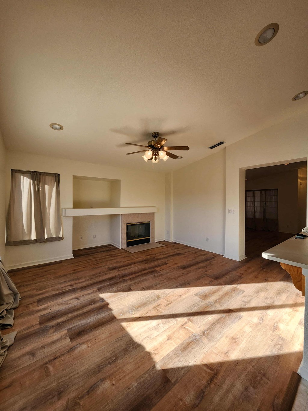 A living room with a fireplace and a ceiling fan.