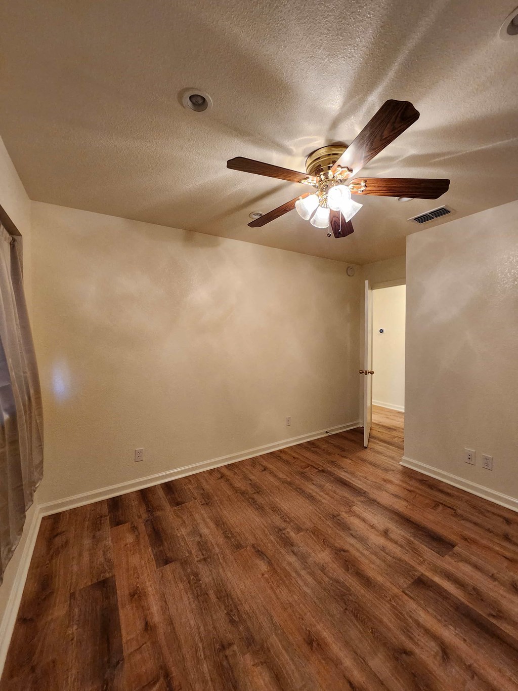 A room with a ceiling fan and wooden flooring.