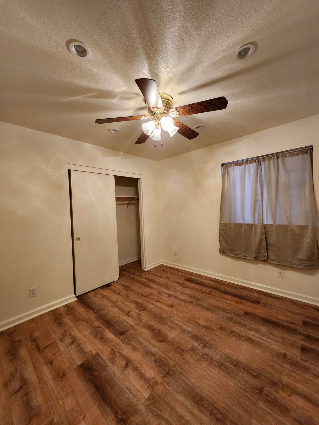A room with a ceiling fan and wooden flooring.