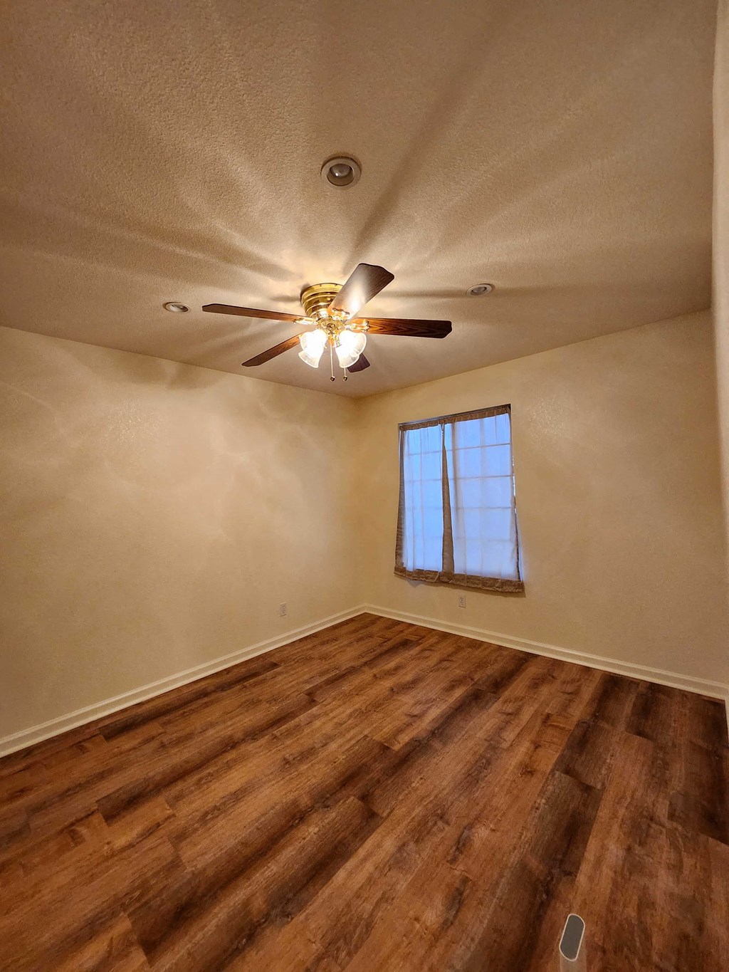 A room with a ceiling fan and wooden flooring.