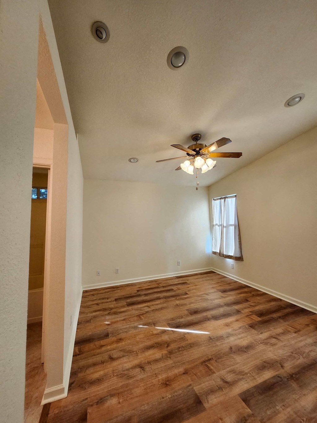 A room with a ceiling fan and wooden flooring.