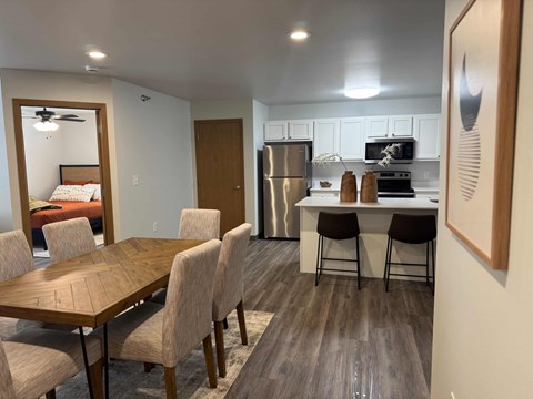 A kitchen with a table and chairs in the foreground and a refrigerator in the background.