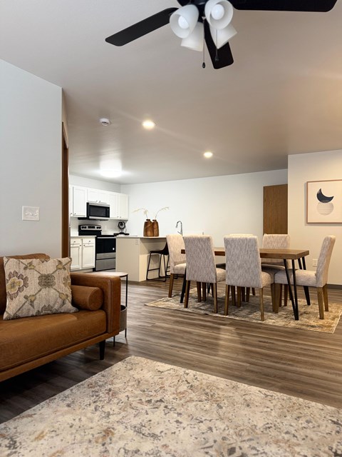 A modern living room with a brown sofa and a dining table set up.