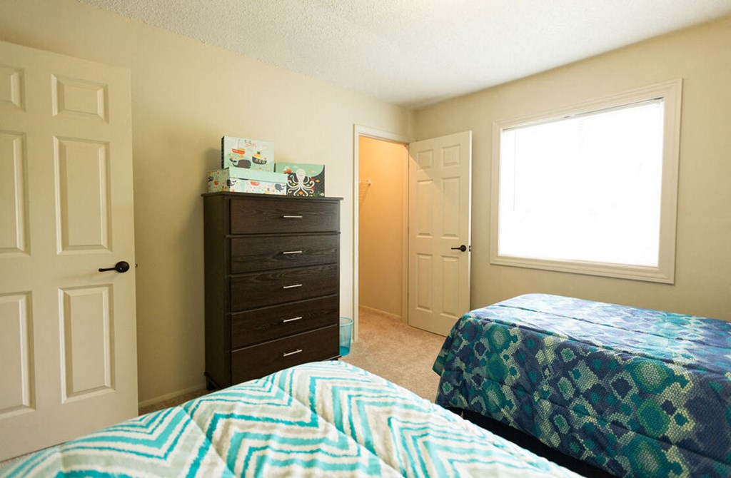 A bedroom with two beds and a dresser.