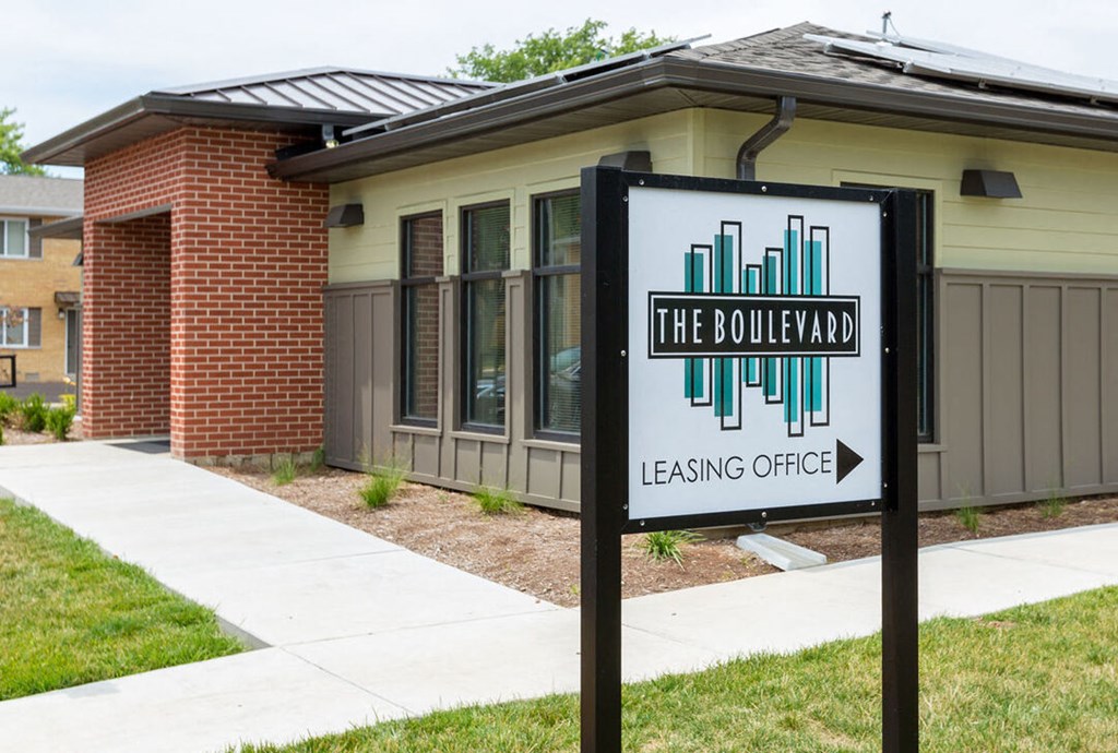 A sign for The Boulevard leasing office in front of a building.