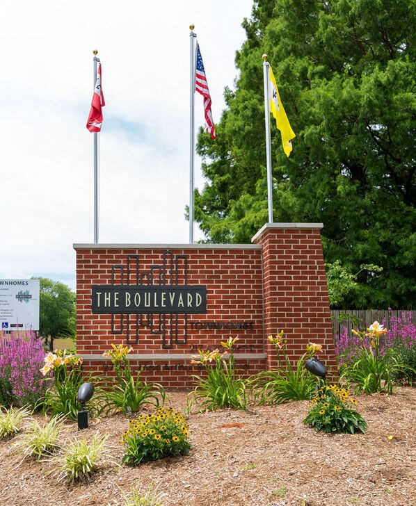 A sign that says "The Boulevard" is in front of some flowers.