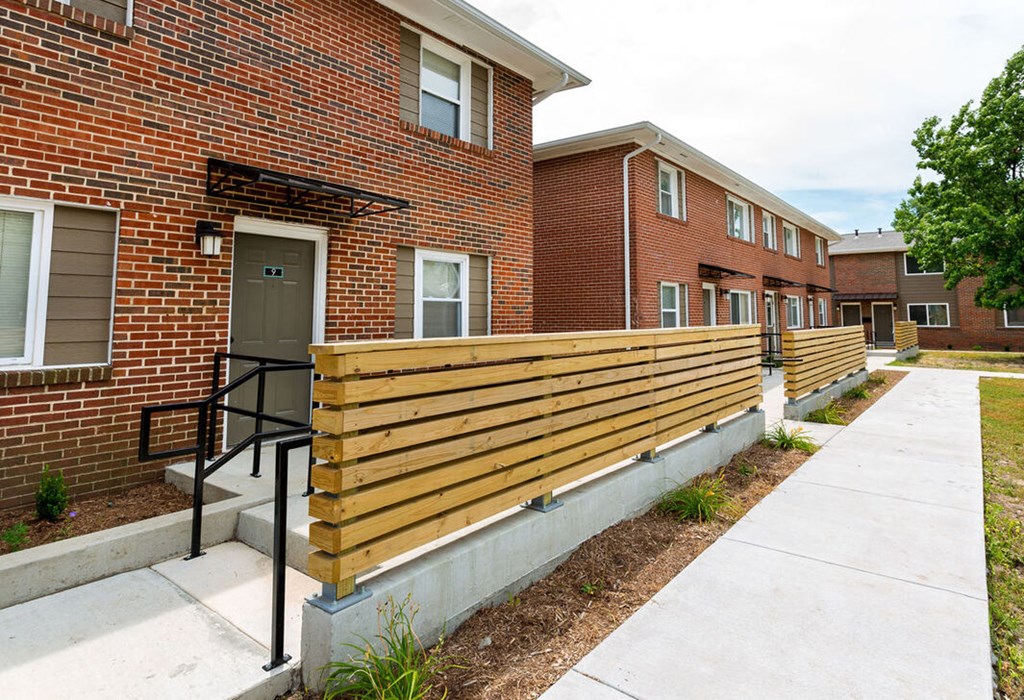 A brick building with a wooden fence and a metal railing.