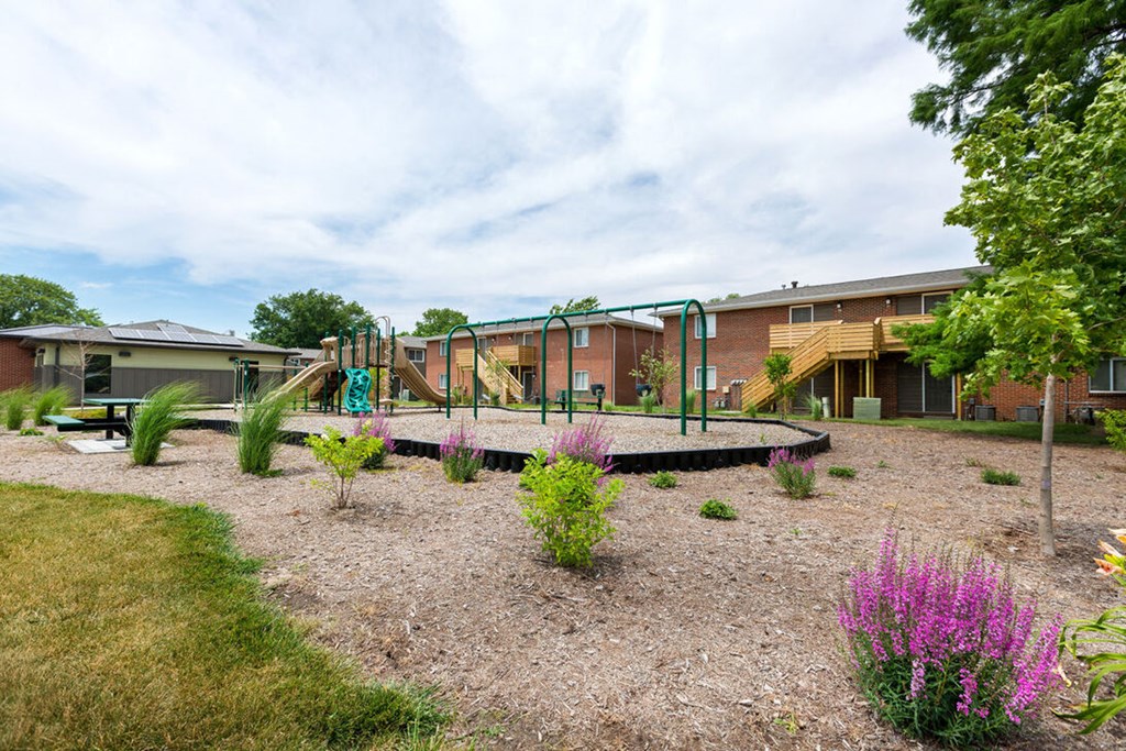 A playground area with a swing set and a slide in front of a building.