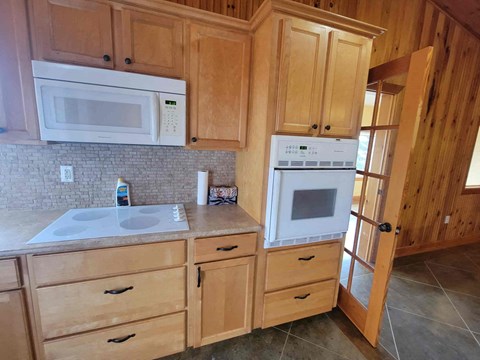A kitchen with wooden cabinets and a white microwave above the stove.