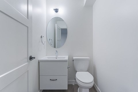 A white bathroom with a toilet, sink, and mirror.