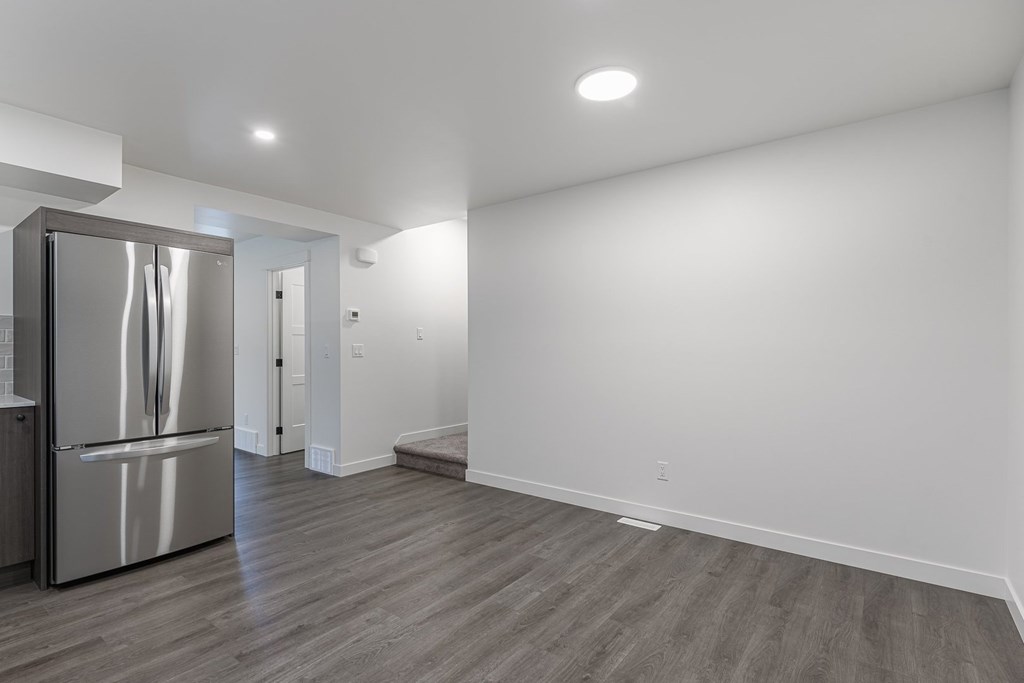 A kitchen with a stainless steel refrigerator and wooden flooring.