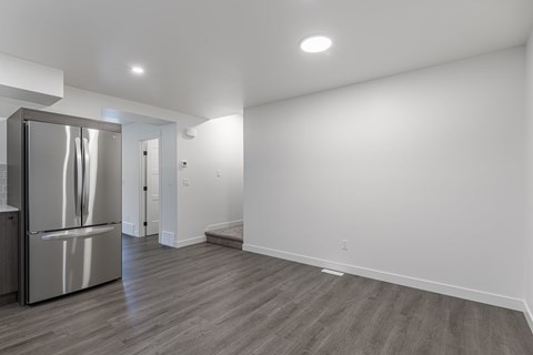 A kitchen with a stainless steel refrigerator and wooden flooring.