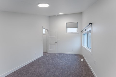 A room with a carpeted floor and a window with blinds.
