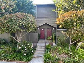 A small house with a red door surrounded by greenery.