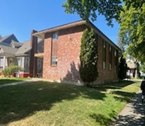 A brick house with a tree in front.