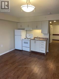 A kitchen with white cabinets and a wooden floor.