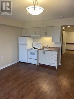 A kitchen with white cabinets and a wooden floor.