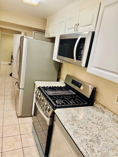 A kitchen with a stove, refrigerator, and microwave.