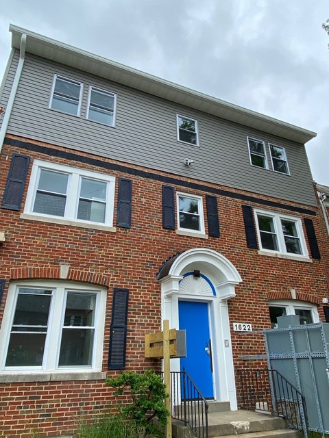A red brick house with a blue door and black shutters.