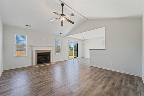 A spacious room with a fireplace and a ceiling fan.