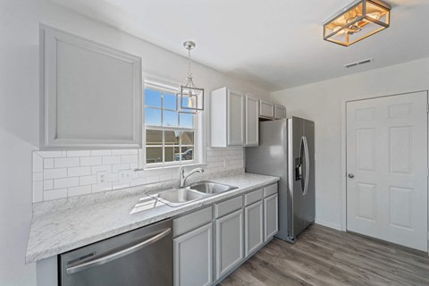 A modern kitchen with a stainless steel refrigerator and a marble countertop.