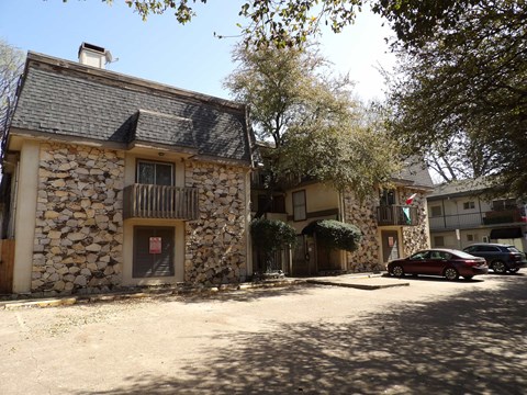 A stone building with a balcony and a car parked in front.