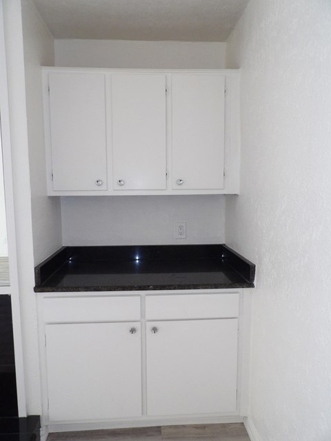 A kitchen with white cabinets and a black countertop.