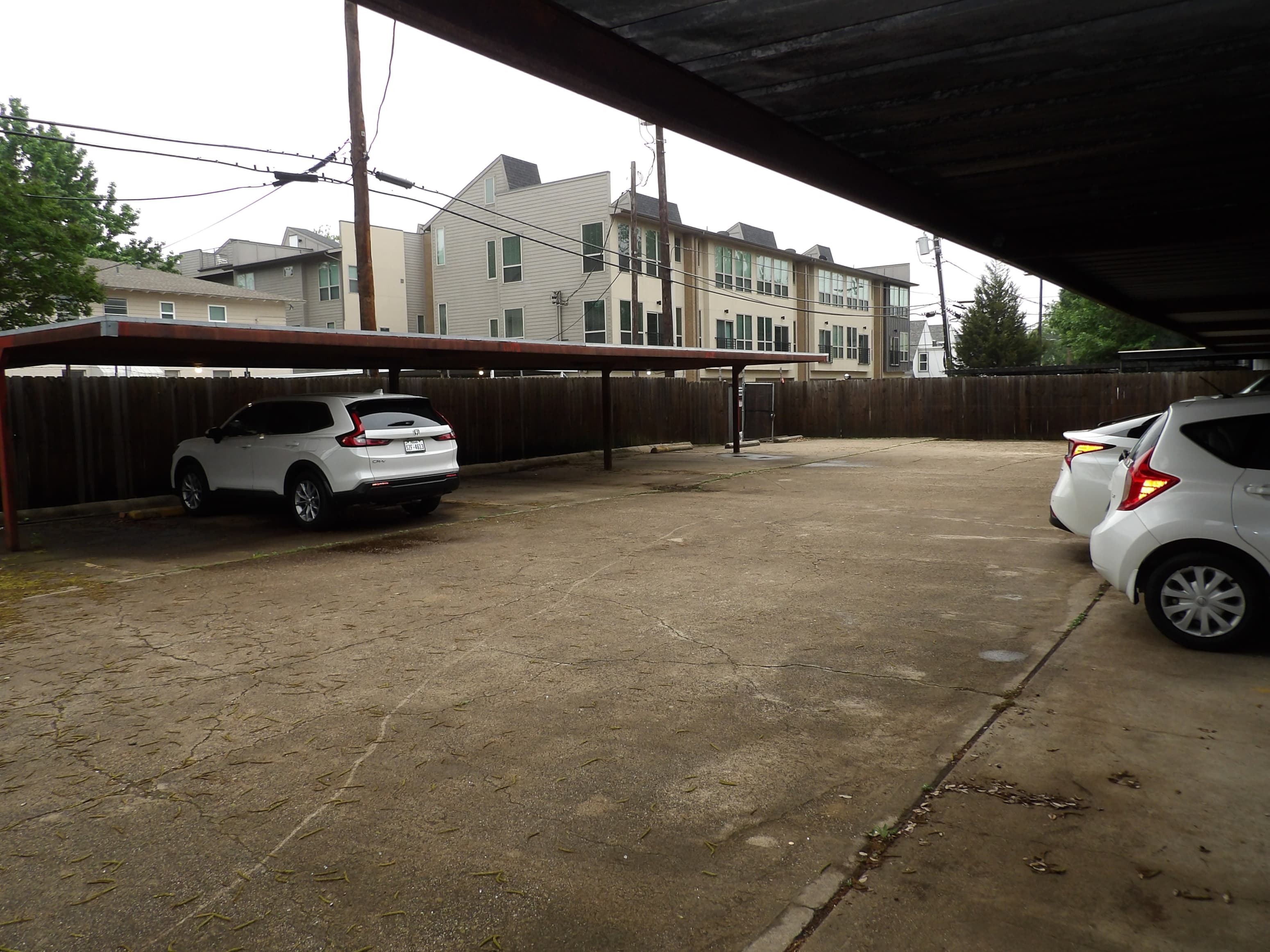A white car is parked in a driveway under a covered area.