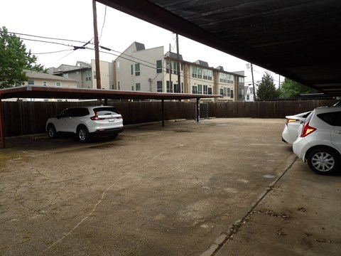 A white car is parked in a driveway under a covered area.