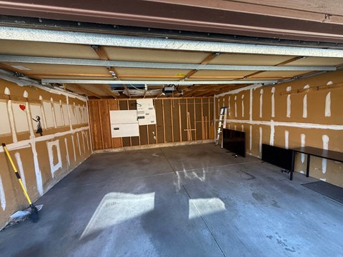A spacious garage with a concrete floor and walls covered in insulation.