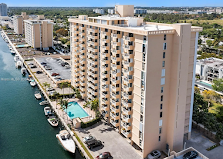 A tall tan building with a pool sits next to a body of water.