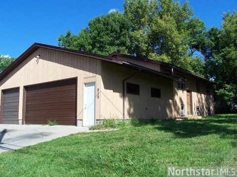 A two-story building with a garage door and a blue door.
