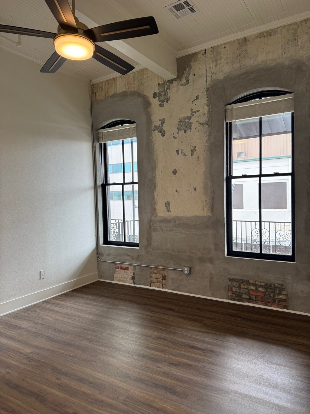 A room with a ceiling fan and wooden floors.