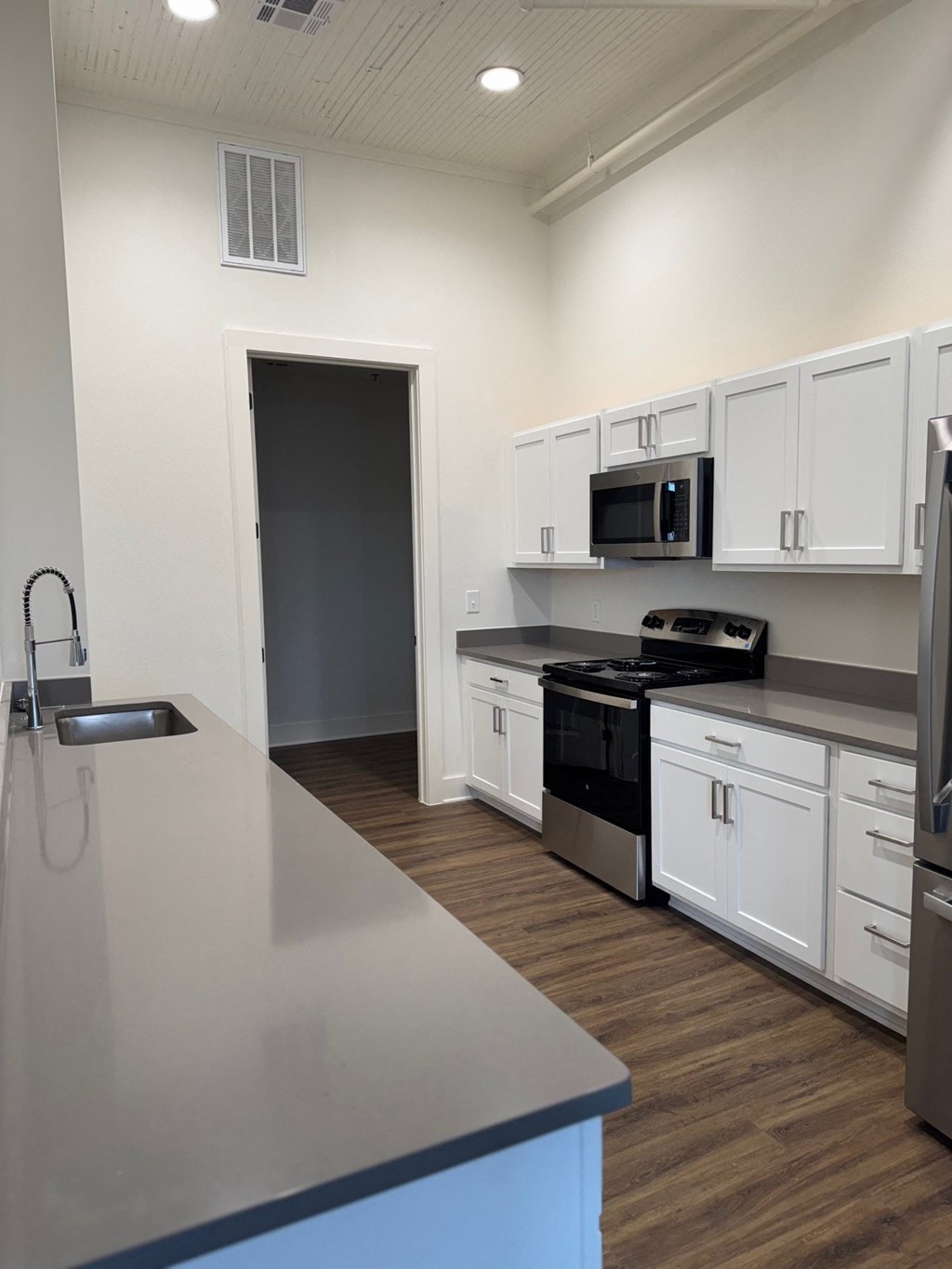 A kitchen with white cabinets and a grey counter top.