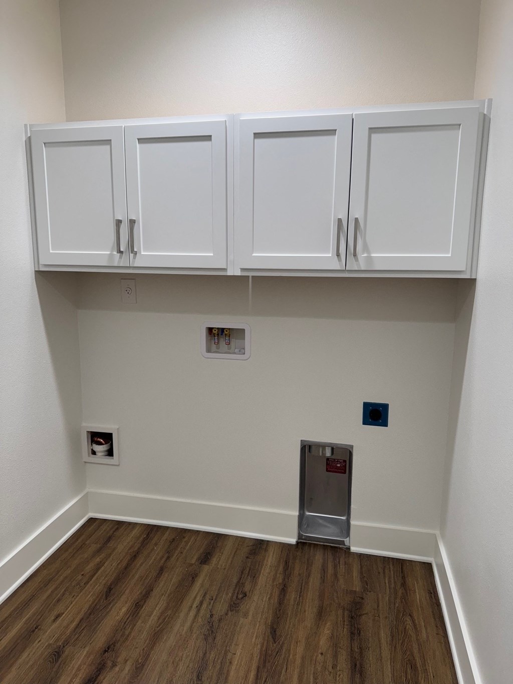 A small white cabinet is in the corner of a room.