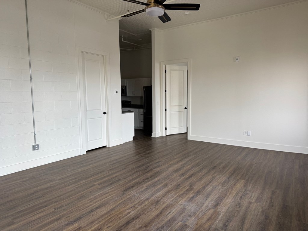A room with a ceiling fan and wooden flooring.