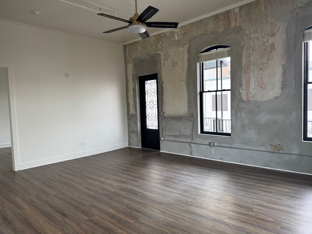 A room with a ceiling fan and wooden flooring.