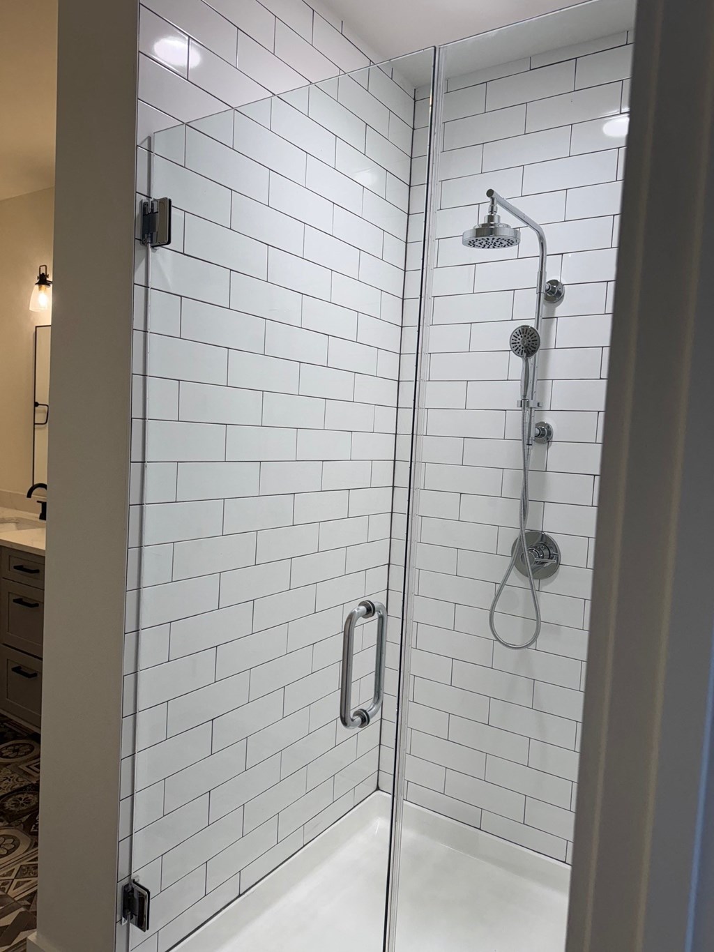 A white tiled shower with a glass door.