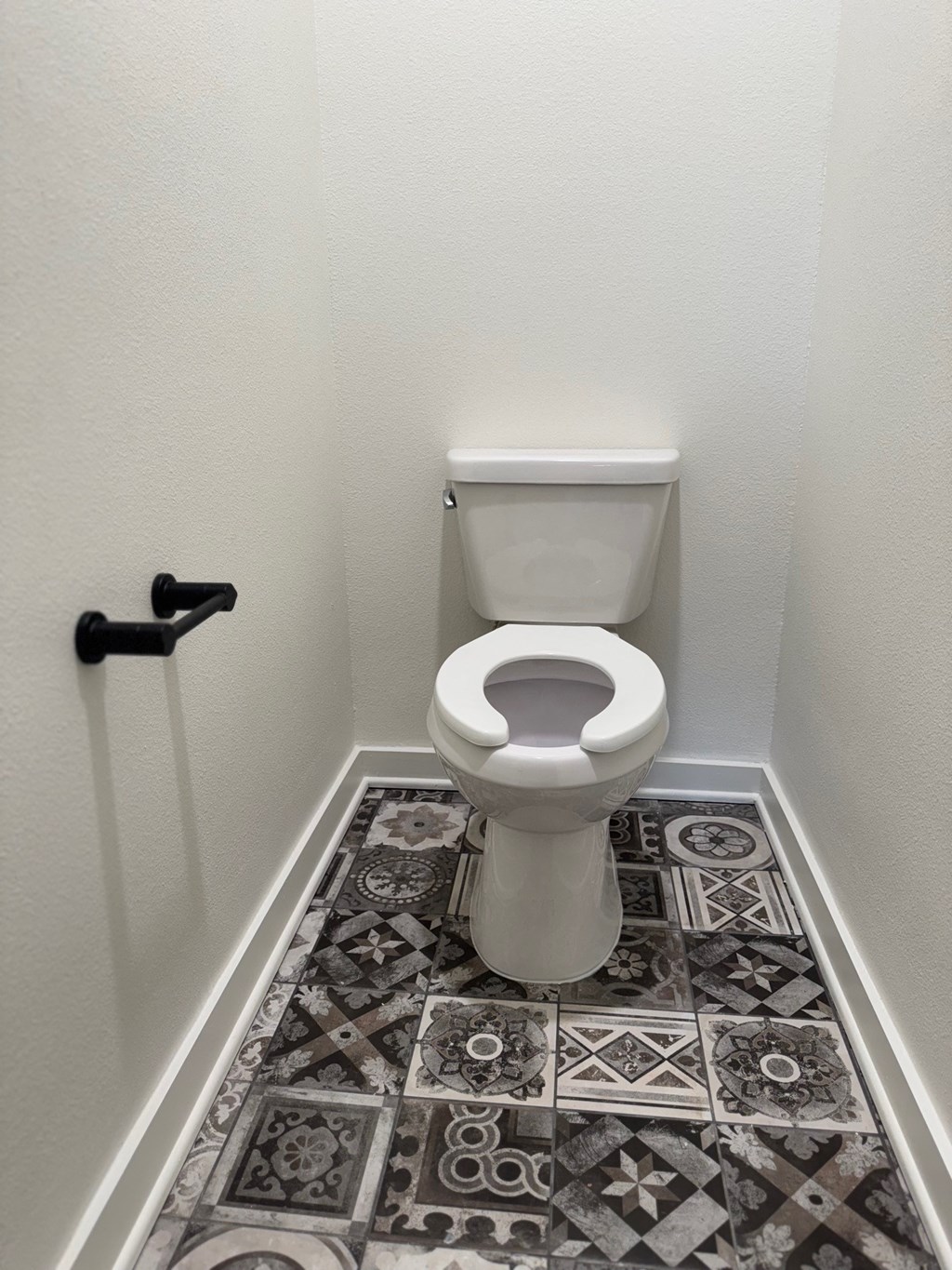 A white toilet in a bathroom with a black and white tiled floor.