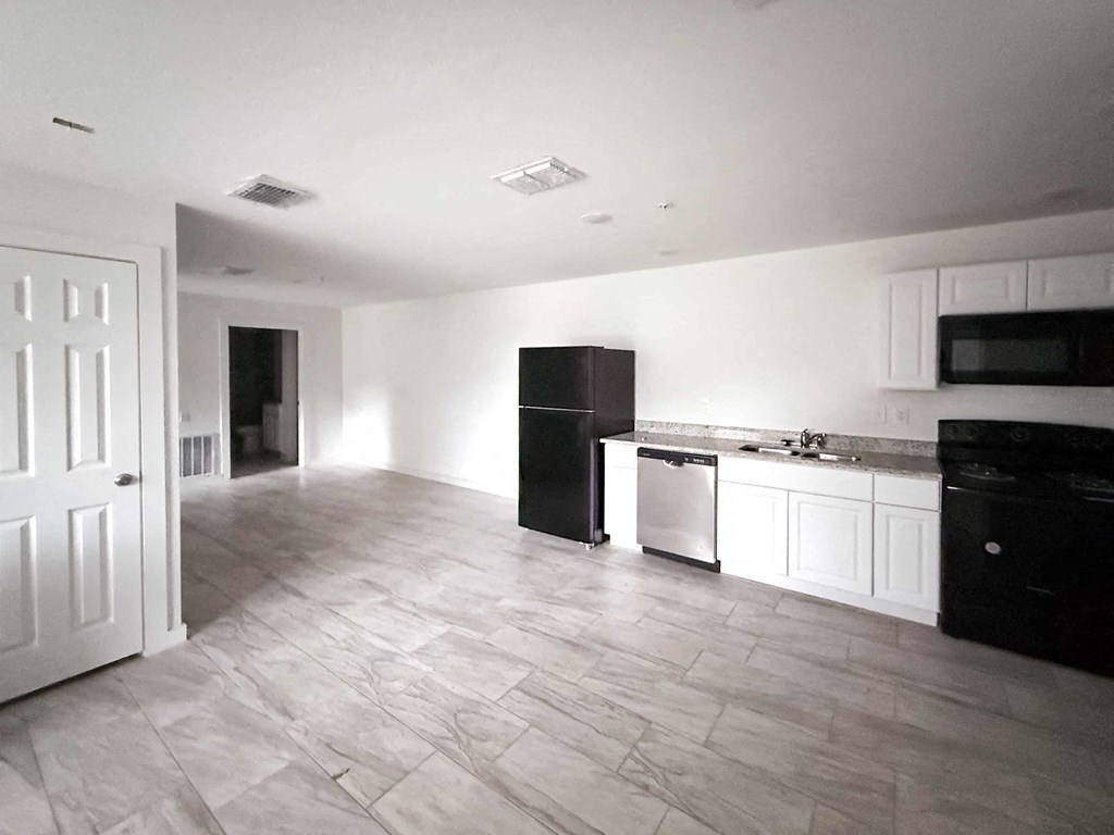 A kitchen with black appliances and white cabinets.