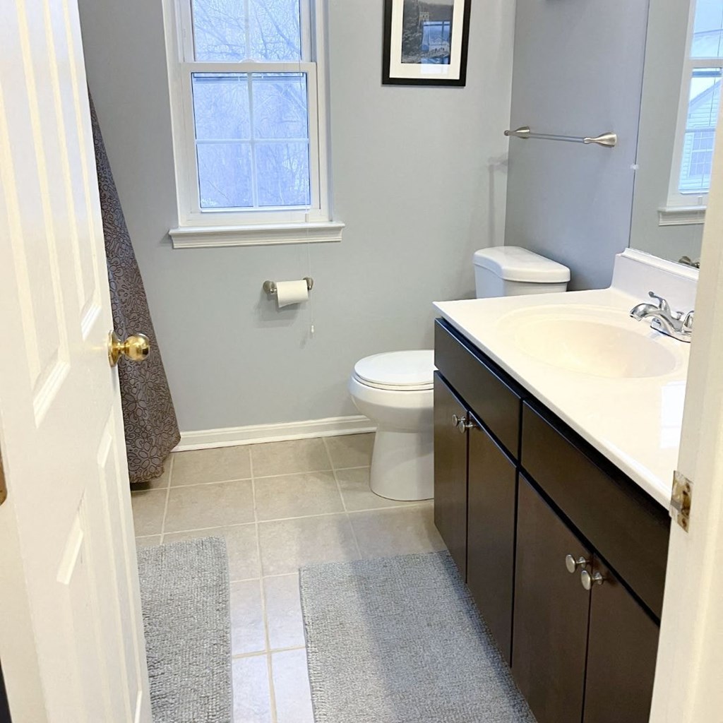 A bathroom with a toilet, sink, and a window.