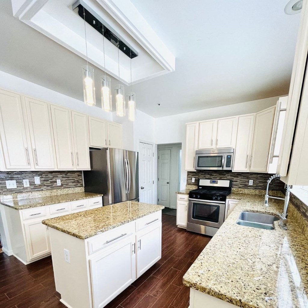 A kitchen with granite countertops and white cabinets.