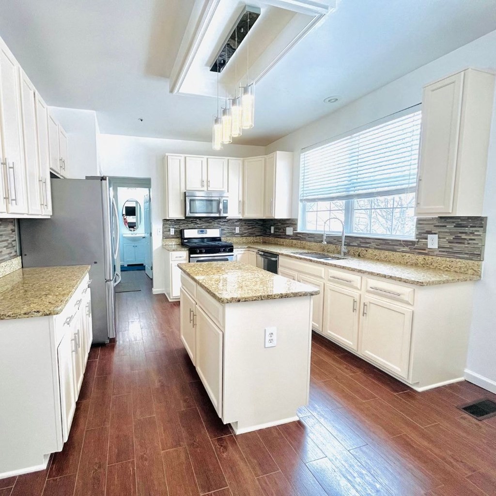 A kitchen with white cabinets and a granite countertop.